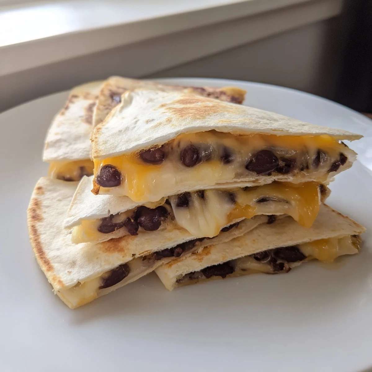 Delicious homemade bean & cheese quesadillas with a savory aroma, perfect for dipping into cool sour cream.