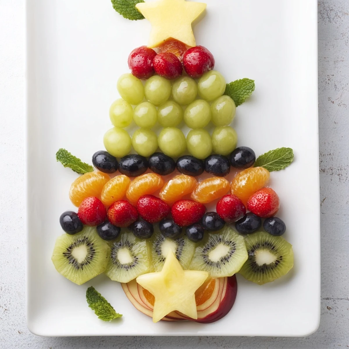 A colorful, easy-to-assemble Quick Christmas Tree Fruit Platter, complete with orange and berry "ornaments."