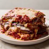 Close-up of delicious Eggplant Parmesan Casserole, browned cheese and savory layers hinting at warm flavors.