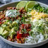 This colorful Turkey Taco Bowl features lettuce, sour cream, and fresh cilantro, served with lime wedges for a zesty squeeze.