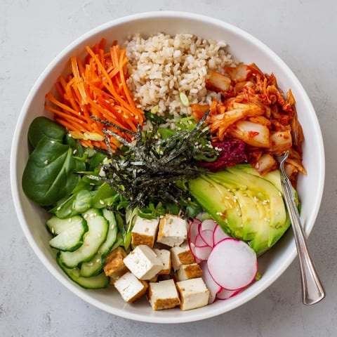 A colorful fermented vegetable bowl with kimchi, fresh greens, and creamy avocado.  