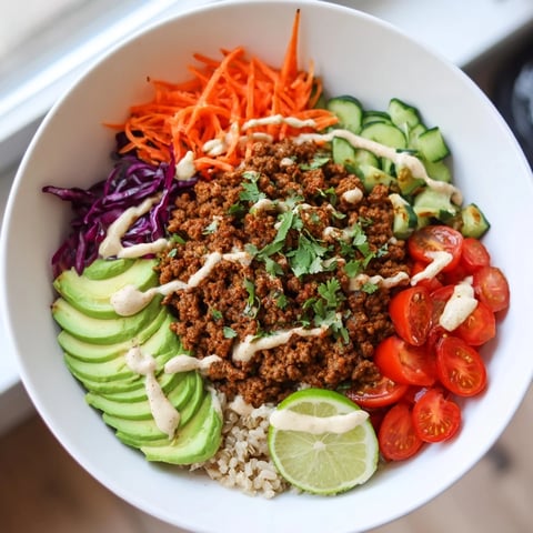 A vibrant plant-based meat bowl topped with fresh vegetables and zesty sauce.