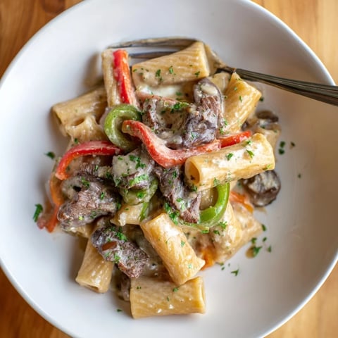 Hearty Philly Cheese Steak Pasta topped with creamy cheese sauce and sautéed peppers.  