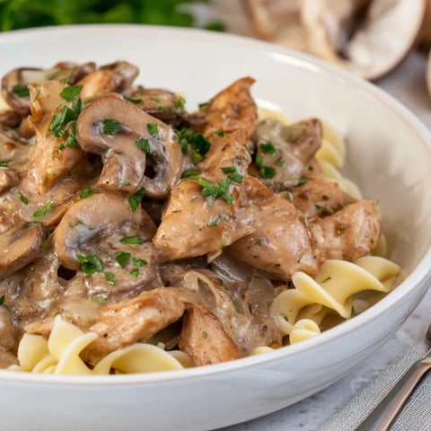 Creamy Chicken Stroganoff served over noodles, topped with fresh parsley and mushrooms.  