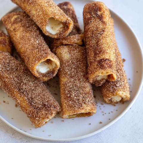 Golden, sugared Easy French Toast Roll-Ups, served warm with a sweet creamy filling for a delicious snack.
