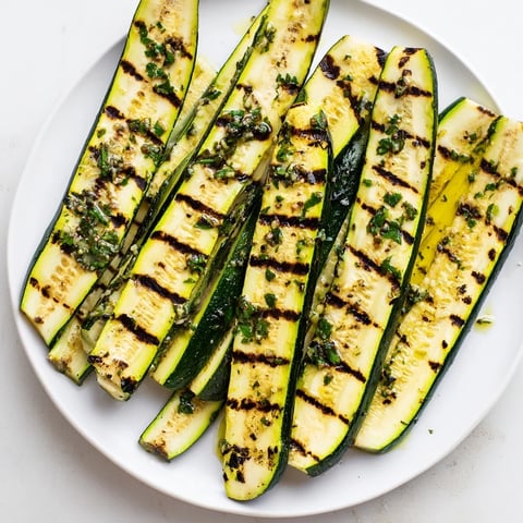 Garlic herb grilled zucchini slices sizzling on a hot grill, ready for a delicious summer side.