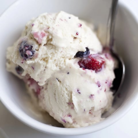A close up of homemade cottage cheese ice cream, swirled with berries, ready to serve.