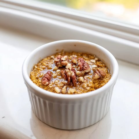 Warm, golden Pumpkin Spice Baked Oats, perfect for breakfast with pecans and a drizzle of maple syrup.