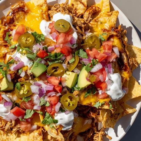 Golden, crispy Loaded Nachos with generous pulled pork, melted queso, spicy jalapeños, and fresh toppings.