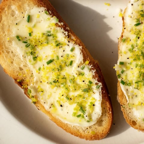 Golden, crispy vodka butter crostini topped with fresh chives and lemon zest, ready for a cocktail party appetizer spread.