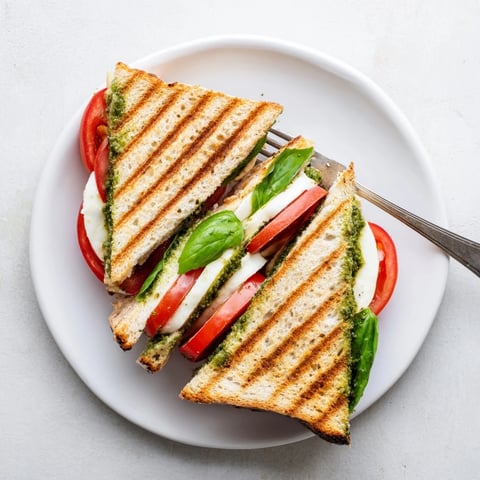Golden-brown panini press innovations with melted mozzarella and fresh tomato slices on crispy ciabatta.  