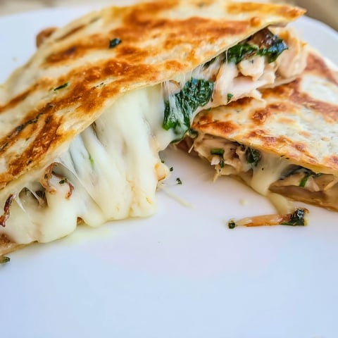 A close-up of a golden, crispy Chicken and Spinach Quesadilla slice with melted mozzarella and vibrant spinach.