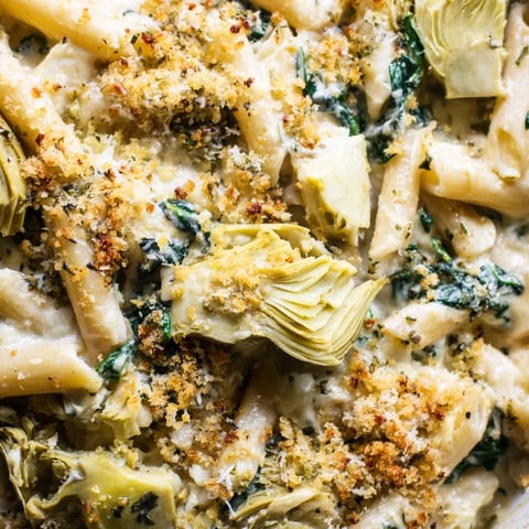 A golden-brown Artichoke Pasta Bake fresh from the oven, bubbling with creamy Parmesan sauce, tender pasta, and vibrant spinach.