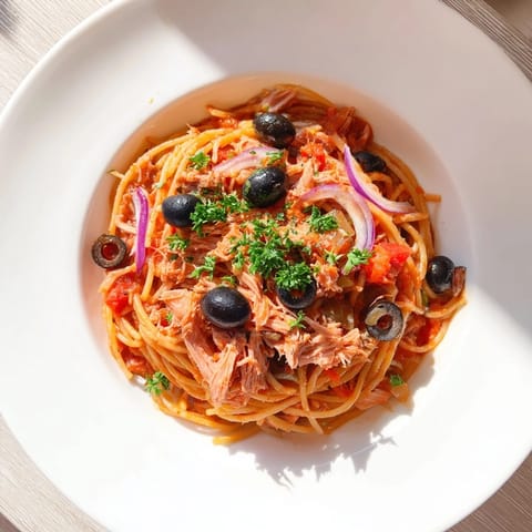 Golden spaghetti noodles tossed with tuna, olives, and capers in a savory tomato-based Pasta with Tuna.