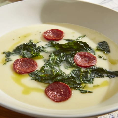 Close-up photo of creamy Portuguese Caldo Verde, showcasing tender kale and savory chorizo pieces.