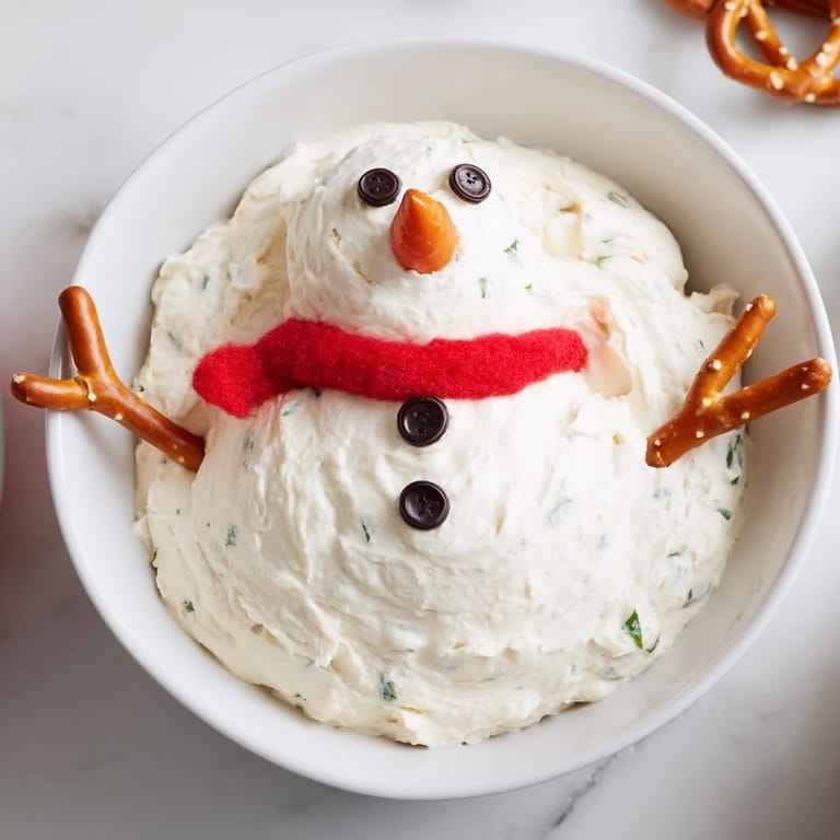 A cheerful view of the melted snowman dip with carrot nose and pretzel arms, perfect for parties.