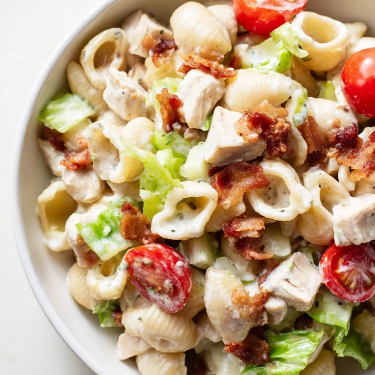 Vibrant BLT Chicken Pasta Salad served chilled, mixing smoky bacon bits, tender chicken, crisp romaine, and juicy tomatoes for a picnic-friendly dish.